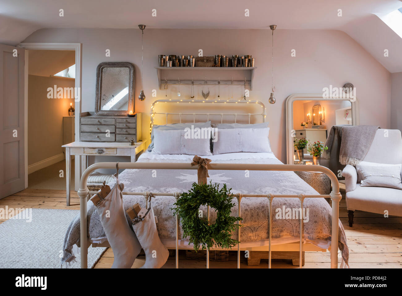 Feather & black's double bed in bedroom with reclaimed wooden flooring and fairy lights Stock Photo