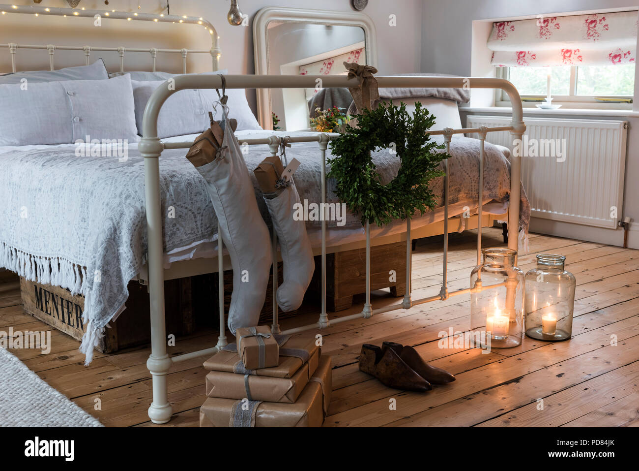 Wrapped presents, stockings and a wreath add a festive touch to a rustic bedroom. The bed is from Feather & black's with Chocolat Menier wooden boxes  Stock Photo