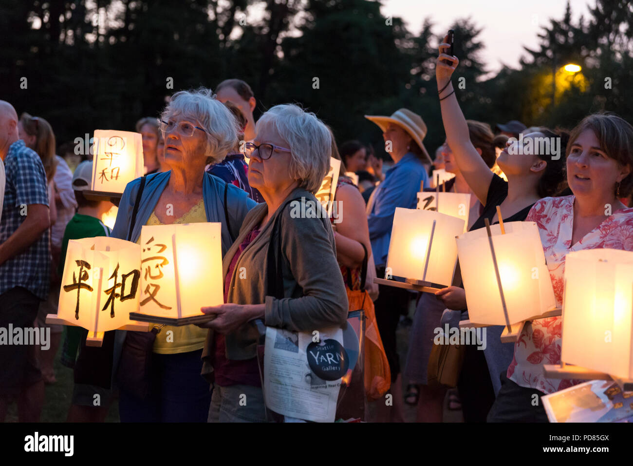 Seattle, Washington: Participants line up with paper lanterns at the From Hiroshima To Hope gathering at Green Lake Park. The ceremony is held in remembrance of atomic bomb victims on the anniversary of the bombing of Hiroshima, Japan. The annual lantern floating ceremony honors victims of the bombings of Hiroshima and Nagasaki, and all victims of violence.  The ceremony is an adaptation of an ancient Japanese Buddhist ritual, the Toro Nagashi, in which lanterns represent Credit: Paul Christian Gordon/Alamy Live News Stock Photo