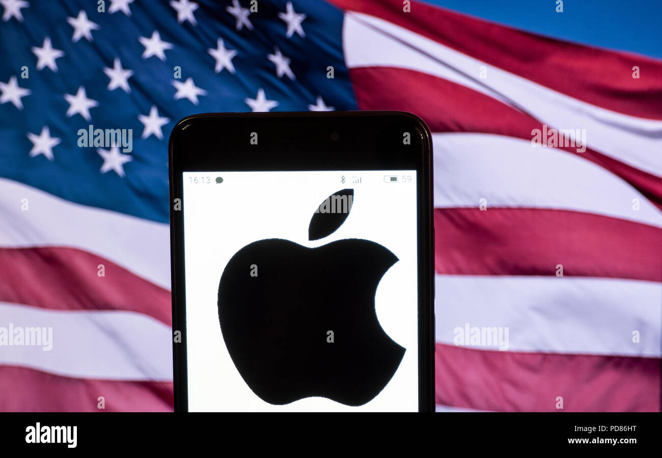 KIEV, UKRAINE - Aug. 5, 2018: The Apple logo seen displayed on a smart phone with a background of an American Flag. Apple's capitalization exceeded $1 trillion Stock Photo