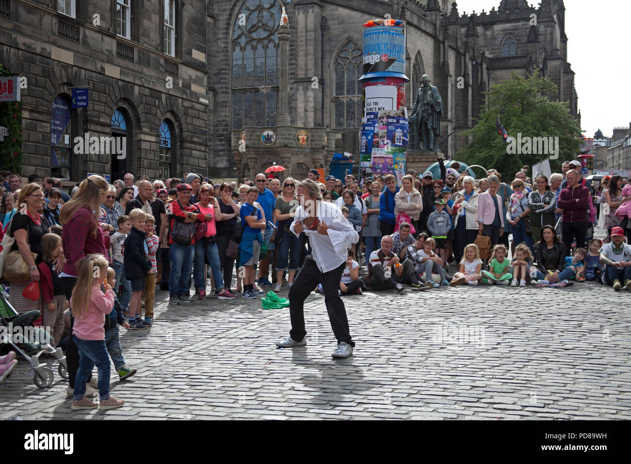 Edinburgh, Scotland UK, 7 August 2018, Edinburgh Fringe on the Royal Mile, on a sunny afternoon the sublime to the ridiculous took to the street with a flashing street statue and a street performers novel way to make use of plumbing plungers and some interesting looking audience members. Silver performing. Stock Photo