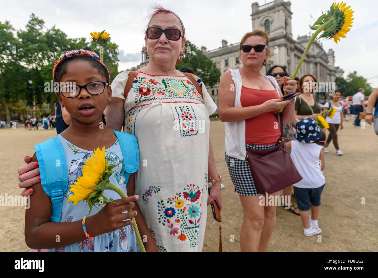 London, UK. 7th August 2018. Colombians hold sunflowers at a  protest in Parliament Square while the names of over a hundered muredred community leaders are read.  The protest in support of the peace process in Colombia demanded an end to the daily threats and murders throughout the country. The International Mobilization for Life and Peace called on the new President of Colombia to put into action an urgent plan to protect social leaders and rapidly implement the peace agreement. Similar actions took place today at the UN in New York, the International Court of Justice in The Hague, and in Wa Stock Photo