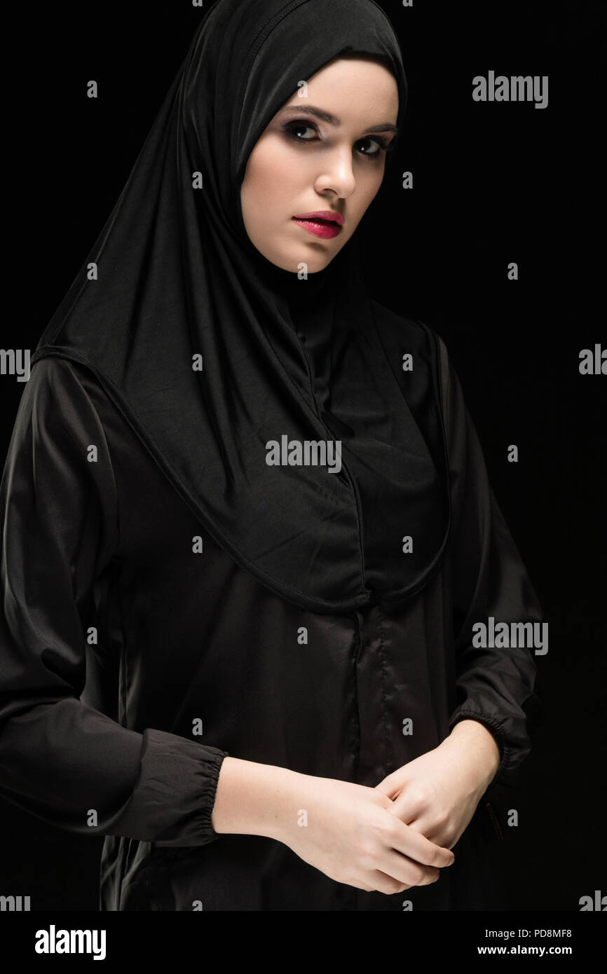 Portrait of beautiful young muslim woman wearing black hijab as conservative fashion concept on black background Stock Photo