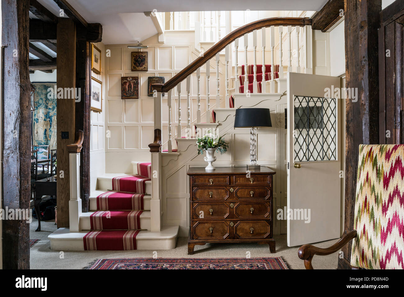 Wood panelled entrance hall with red carpet runner, 18th century oak