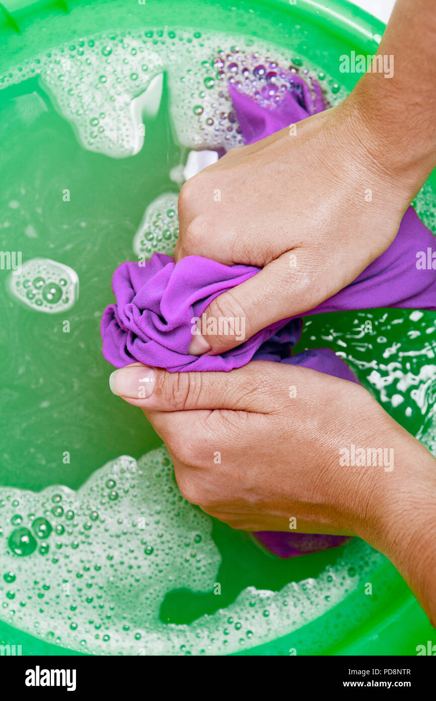 Image on top of girl hands washing violet clothes in green basin Stock Photo