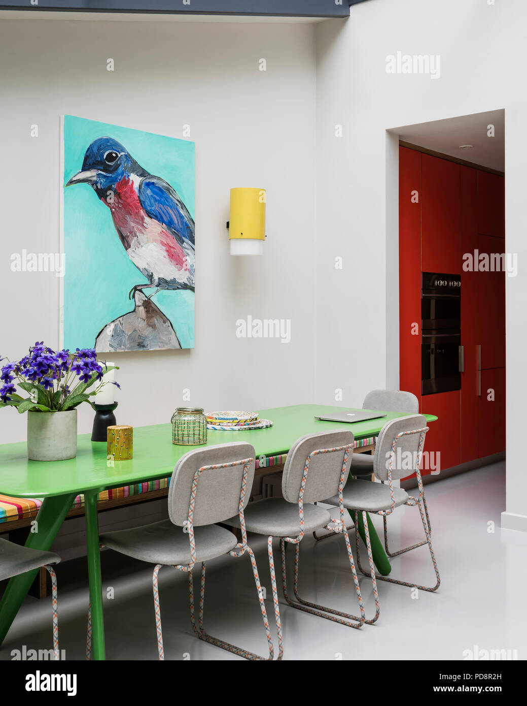 Bird portrait by James Franco keeps watch over the custom green-painted table by Tom Dixon and chairs from Moooi. Stock Photo