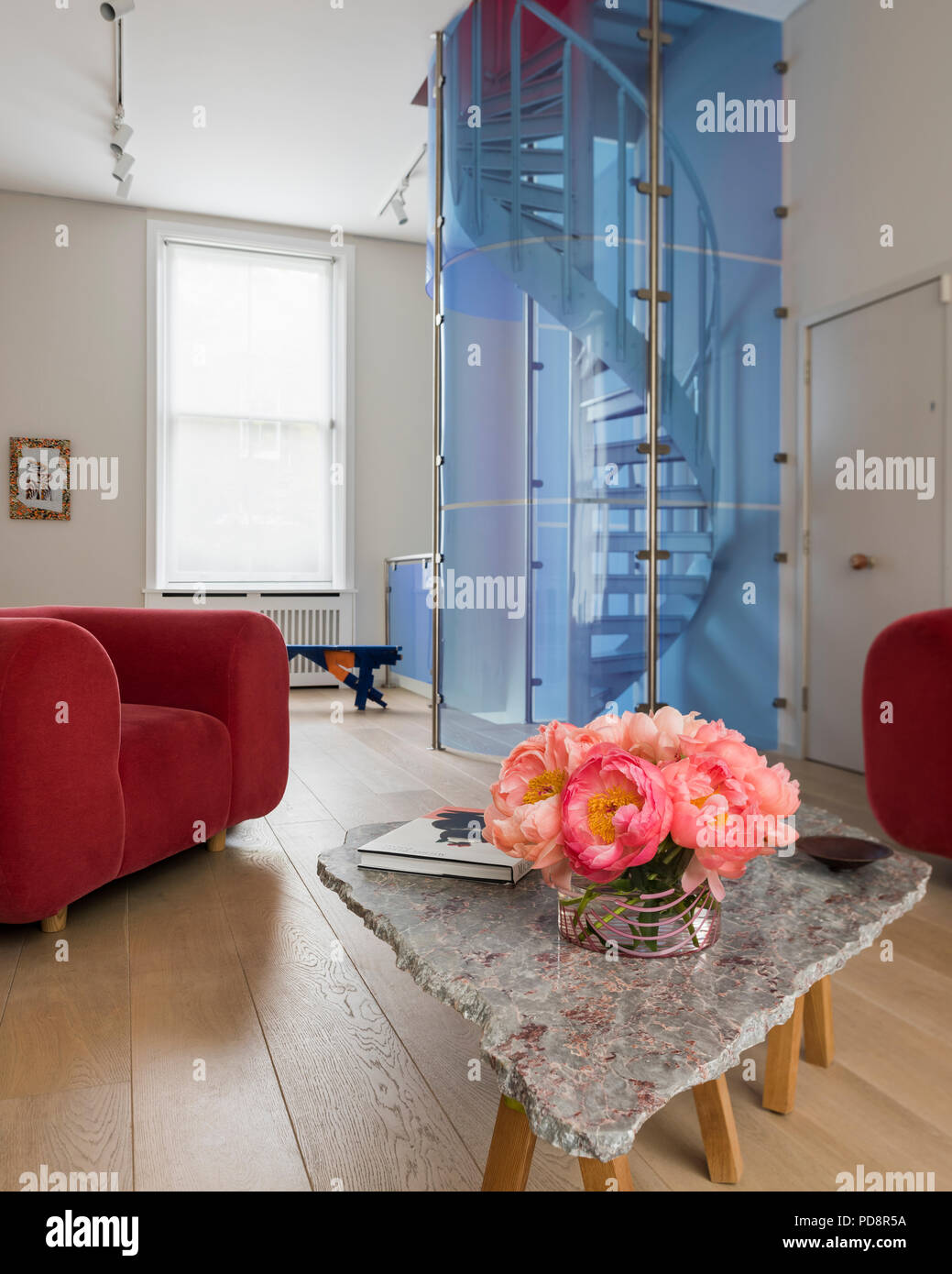 Pink velvet chair and sofa by Tom Dixon, floor lamp by artist Anton Alvarez and blue plexiglass spiral staircase with polished stone topped table by G Stock Photo