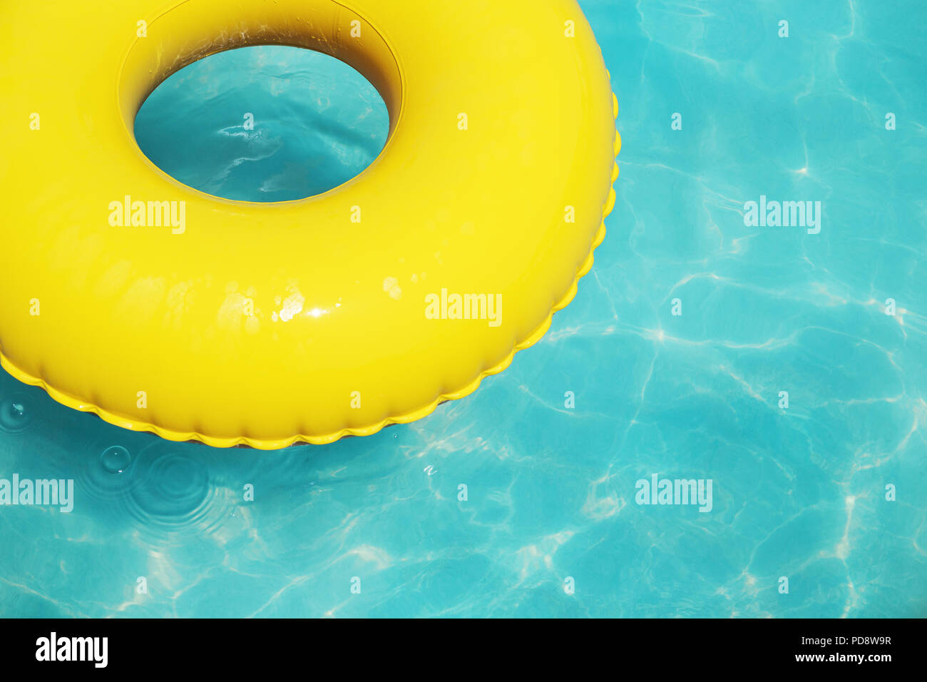 Yellow swimming ring on aqua blue water. Trendy colors, abstract summer background with copy space. Vacation, minimal. Stock Photo