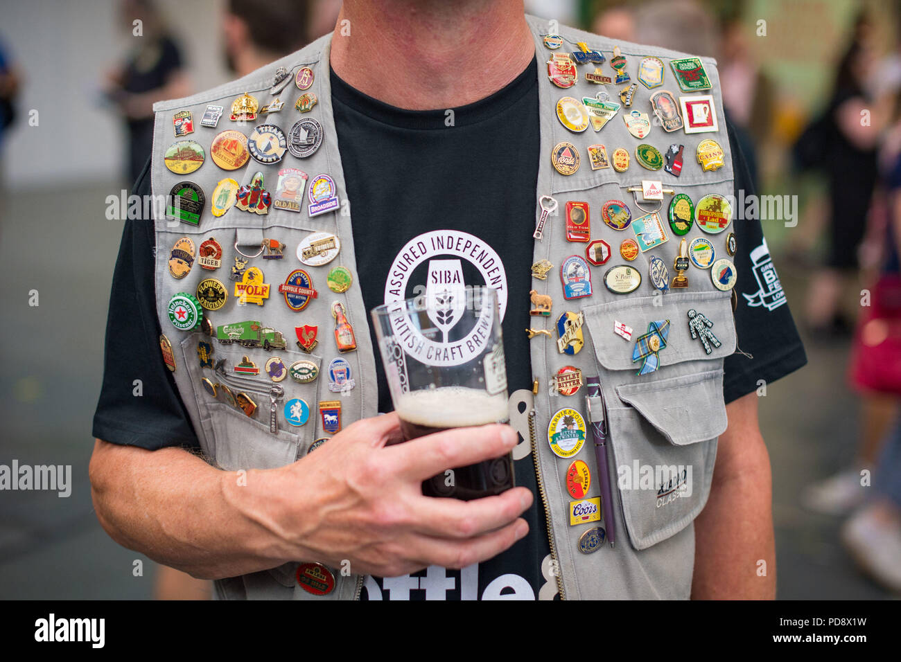 A visitor wearing a jacket covered in brewery and beer badges during the CAMRA Great British Beer Festival at Olympia in London, to sample craft beers and real ales from around the world. Stock Photo