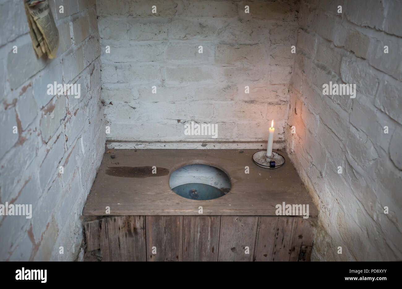Interior of old-fashioned, non-flushing bucket toilet in brick-built outhouse. Pail privy, pail closet close up (Rochdale system). Toilet newspaper. Stock Photo