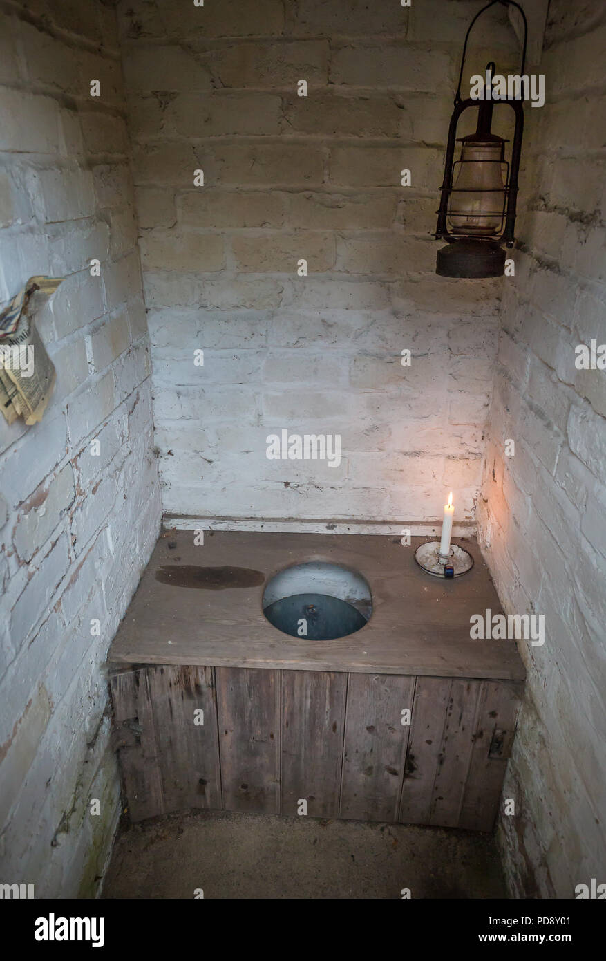 Interior of old-fashioned, non-flushing bucket toilet in brick-built outhouse. Pail privy, pail closet close up (Rochdale system). Toilet newspaper. Stock Photo