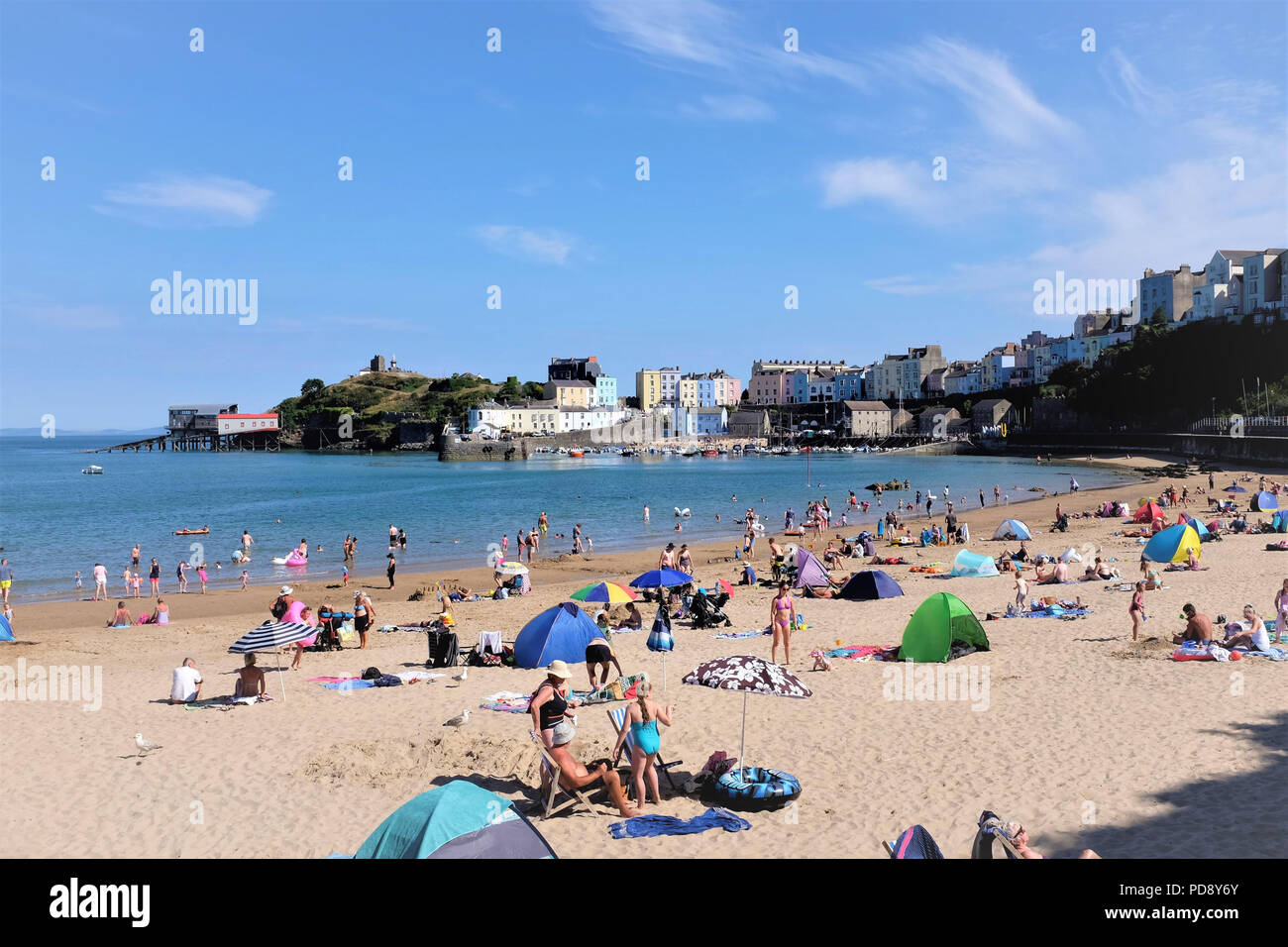 Tenby, Pembrokeshire, South Wales, UK. July 26, 2018.  Holidaymakers enjoying the North beach looking towards the town and harbor of Tenby in South Wa Stock Photo