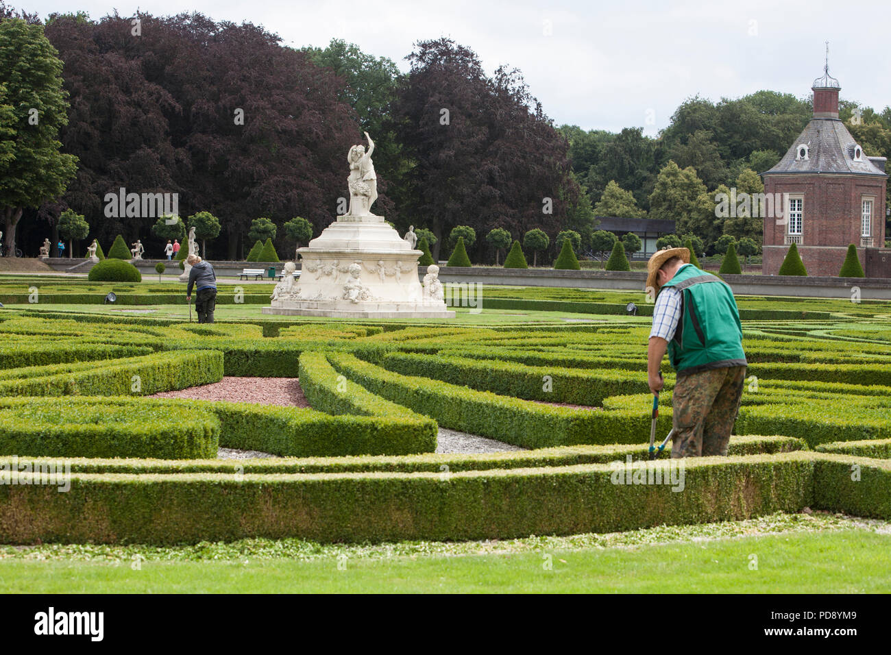Gardener cutting the low boxwood hedges at Nordkirchen Moated Palace, Germany Stock Photo