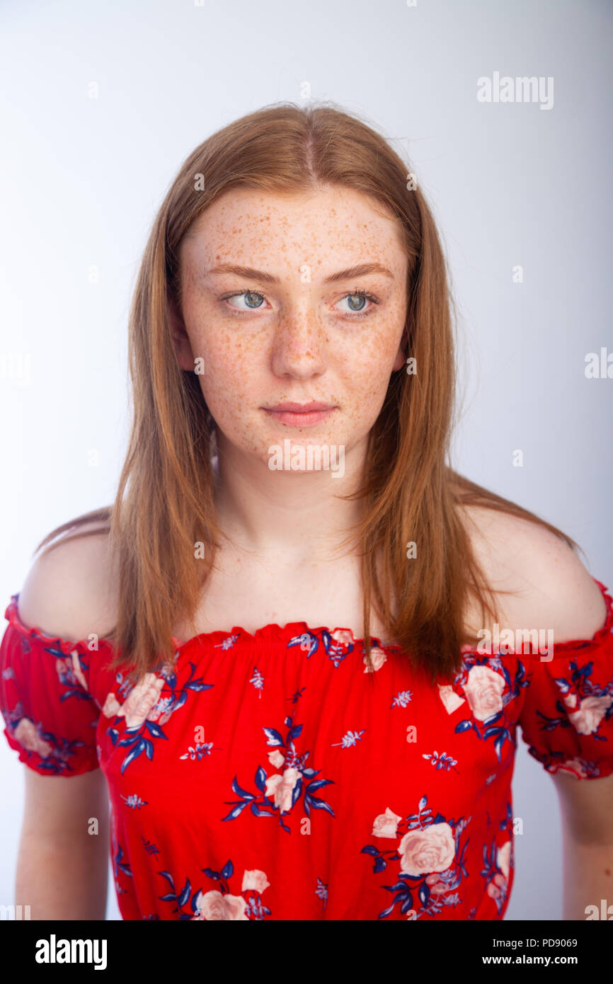 Portrait of a pretty teenage girl with red hair and freckles looking
