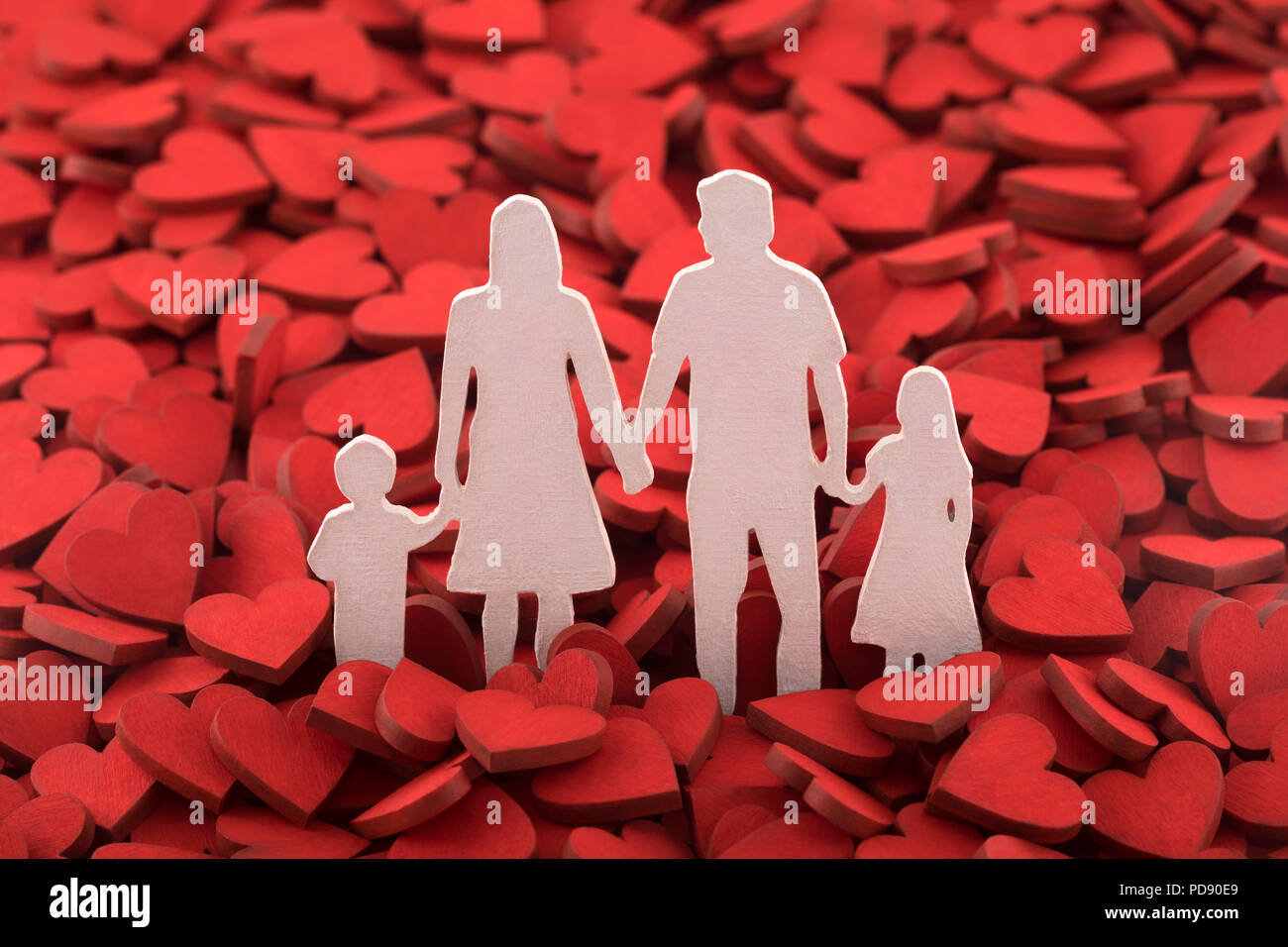 Love and happy family concept. Family figure over hundreds of red hearts. Stock Photo