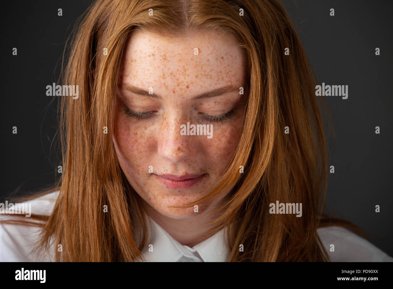 Close up of a red headed girl with freckles with her eyes closed. Stock Photo