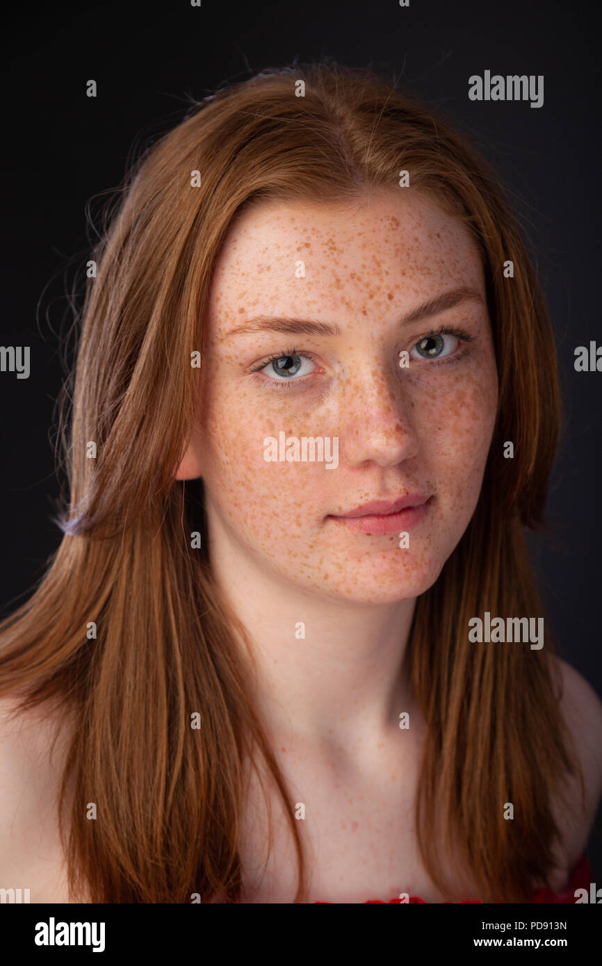 Portrait of a pretty teenage girl with red hair and freckles looking towards camera. Stock Photo