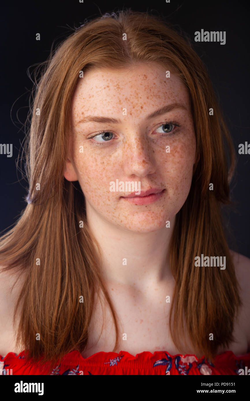 Portrait of a pretty teenage girl with red hair and freckles looking away from camera. Stock Photo