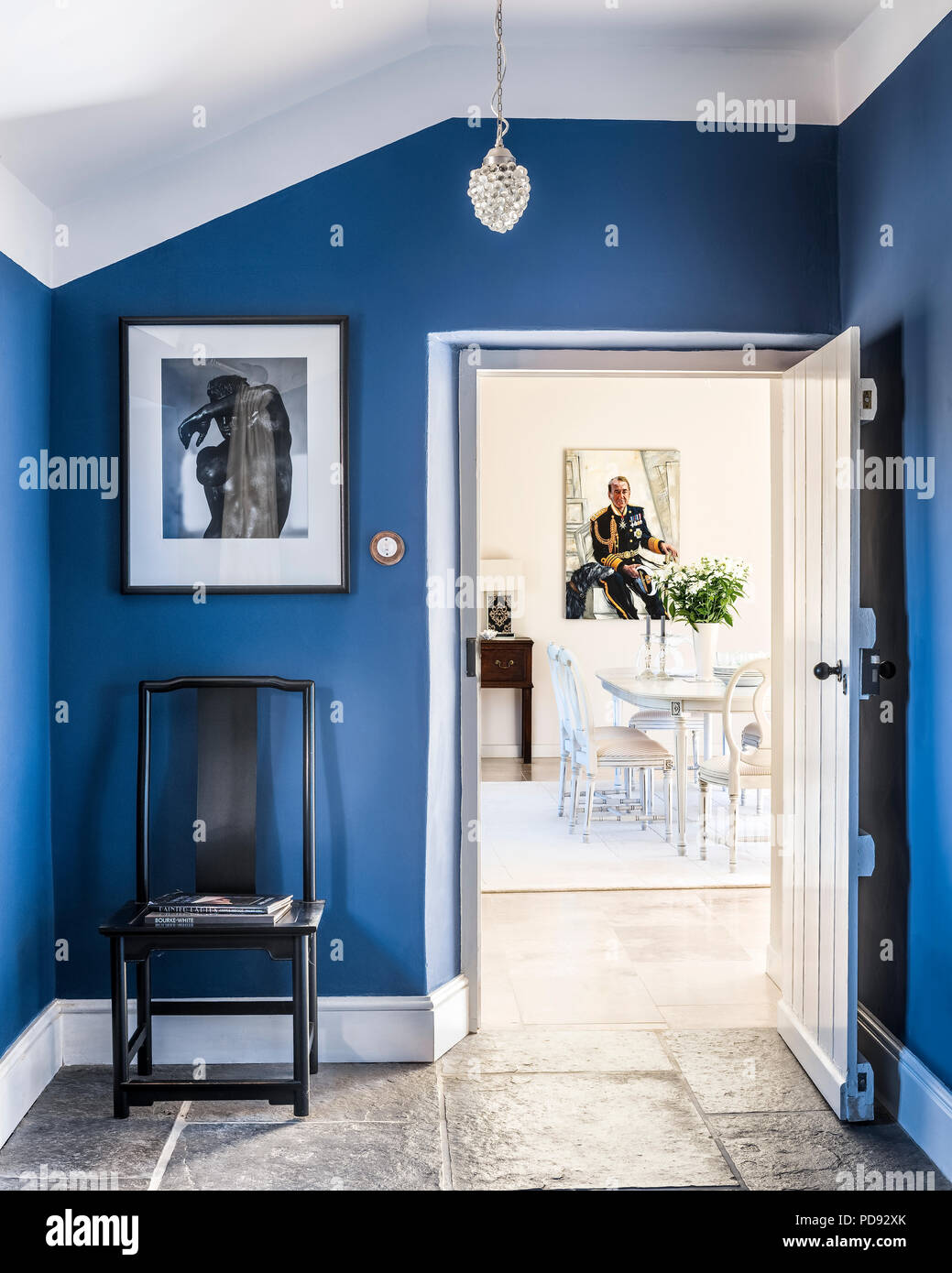 View through blue entrance hall to bright and airy dining room. A James Wedge painting hangs at the far end. the ceiling light is Immy by Laura Ashley Stock Photo