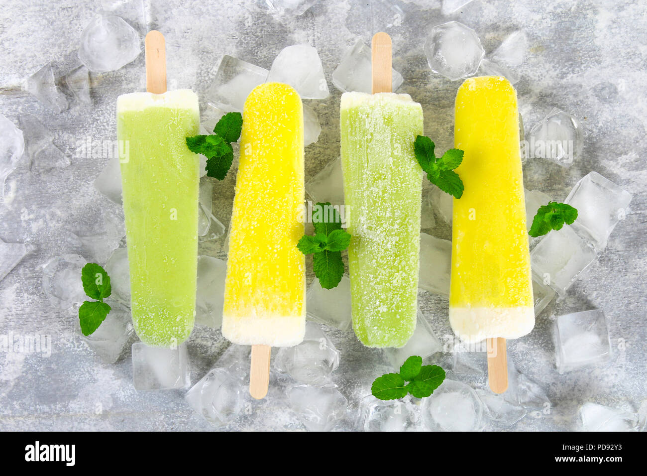 Yellow and green fruit ice cream on a stick on ice on a light table Stock  Photo - Alamy
