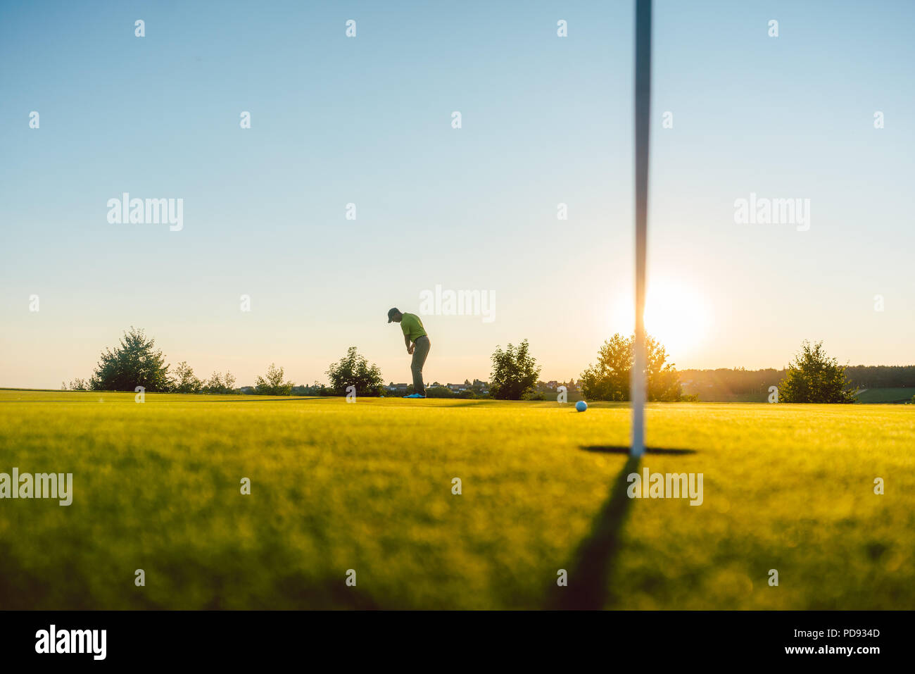 Silhouette of a male player hitting a long shot on the golf course Stock Photo