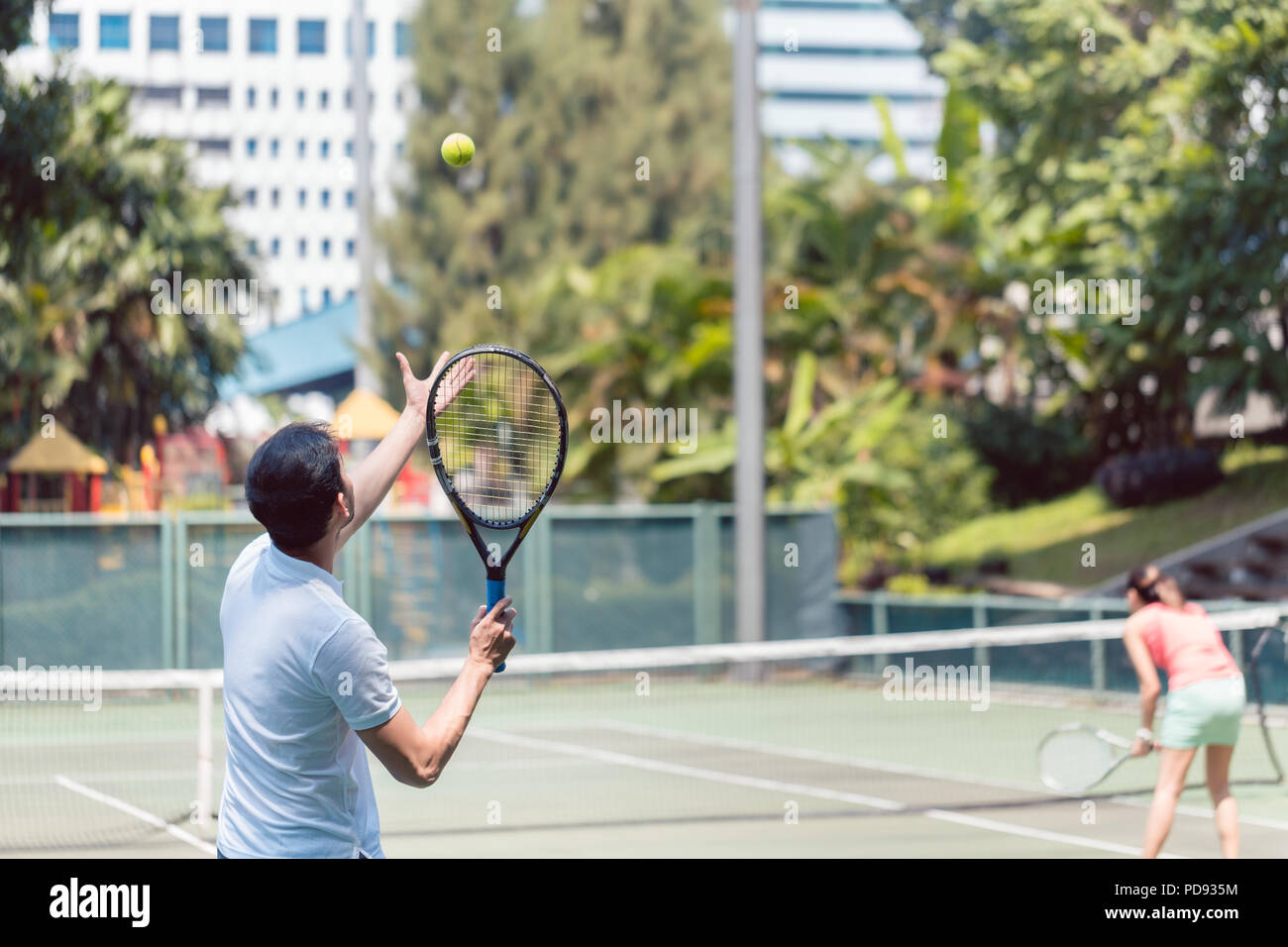 Rear view of a man ready to serve during doubles match Stock Photo