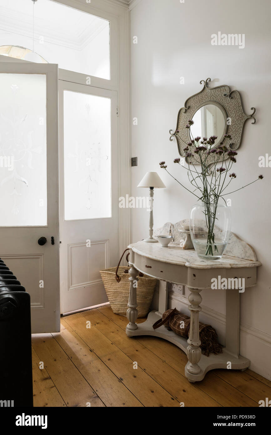 Marble topped console table in white entrance hall with wooden flooring. Stock Photo