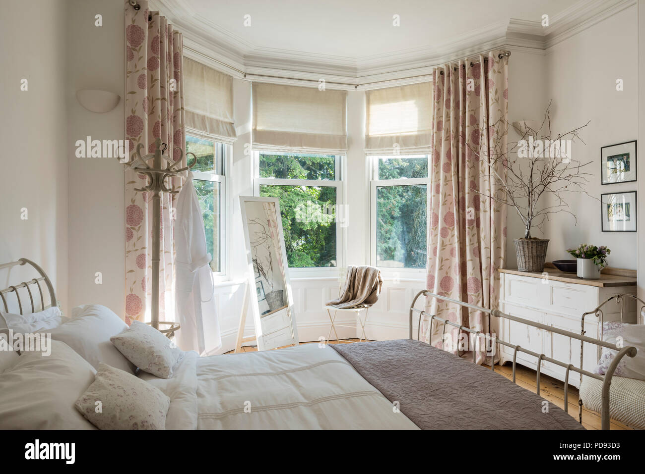 French inspired guest bedroom with iron framed bed. The bedding is from the white company and the cushion fabric is from Cabbages and Roses Stock Photo