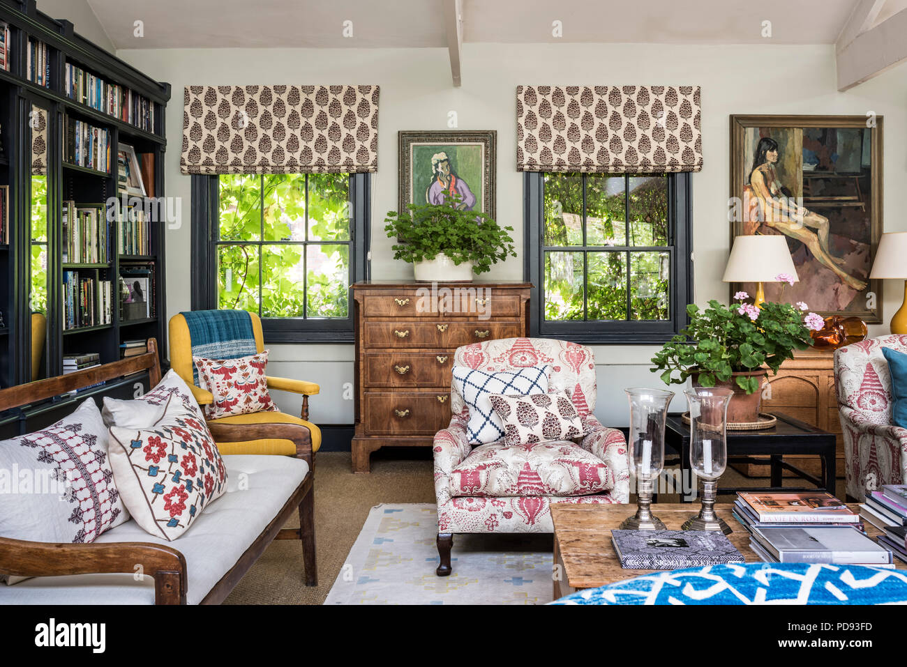 A late Georgian chest of drawers in living room witha pair of original  Howard armchairs, a South African bench and a large sofa. The left side  paintin Stock Photo - Alamy