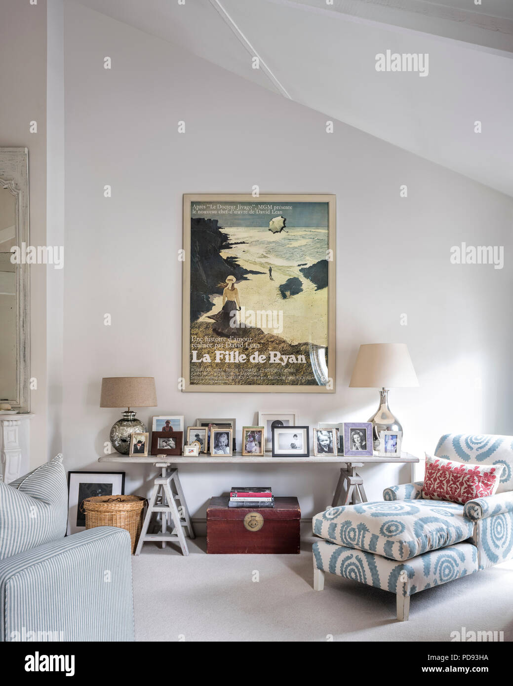 A large vintage film poster on wall of bedroom. The chaise is upholstered in printed linen from Penny Morrison Stock Photo