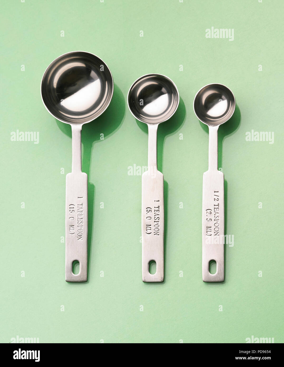Group of measuring spoons on a pale green background Stock Photo
