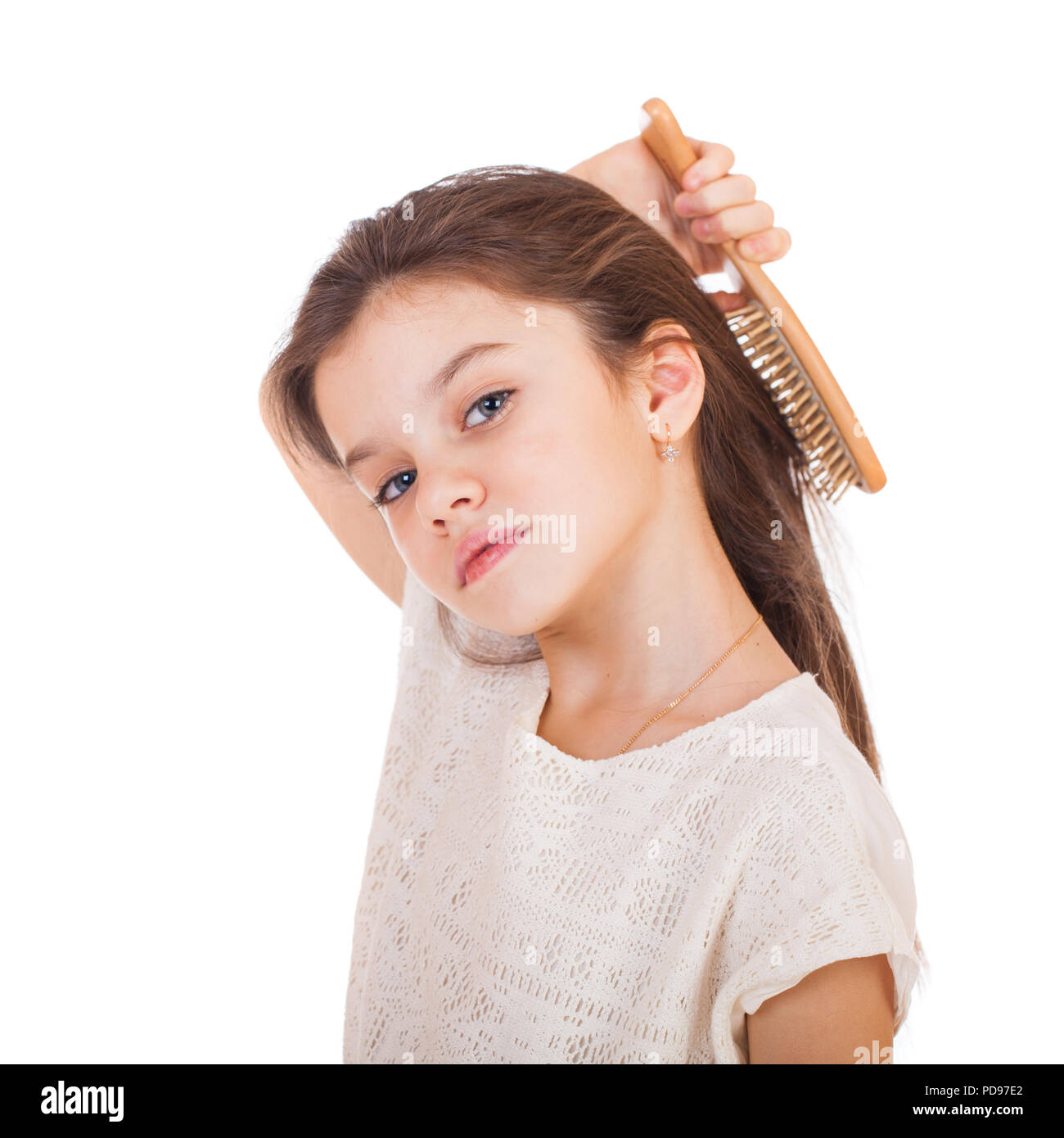 Hair care concept with portrait of little brunette girl brushing her unruly, tangled long hair isolated on white Stock Photo