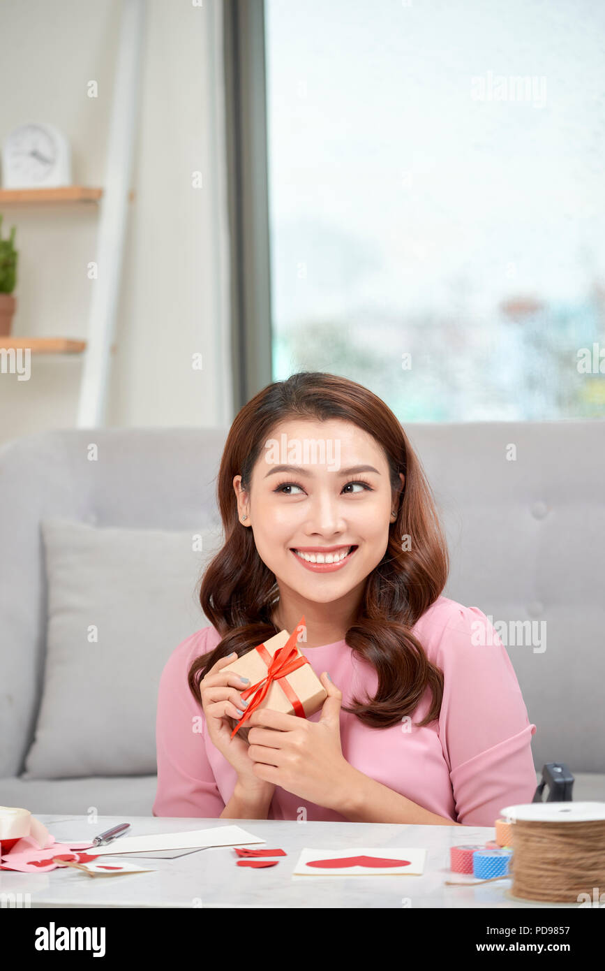 Happy young woman pressing gift box to her chest Stock Photo