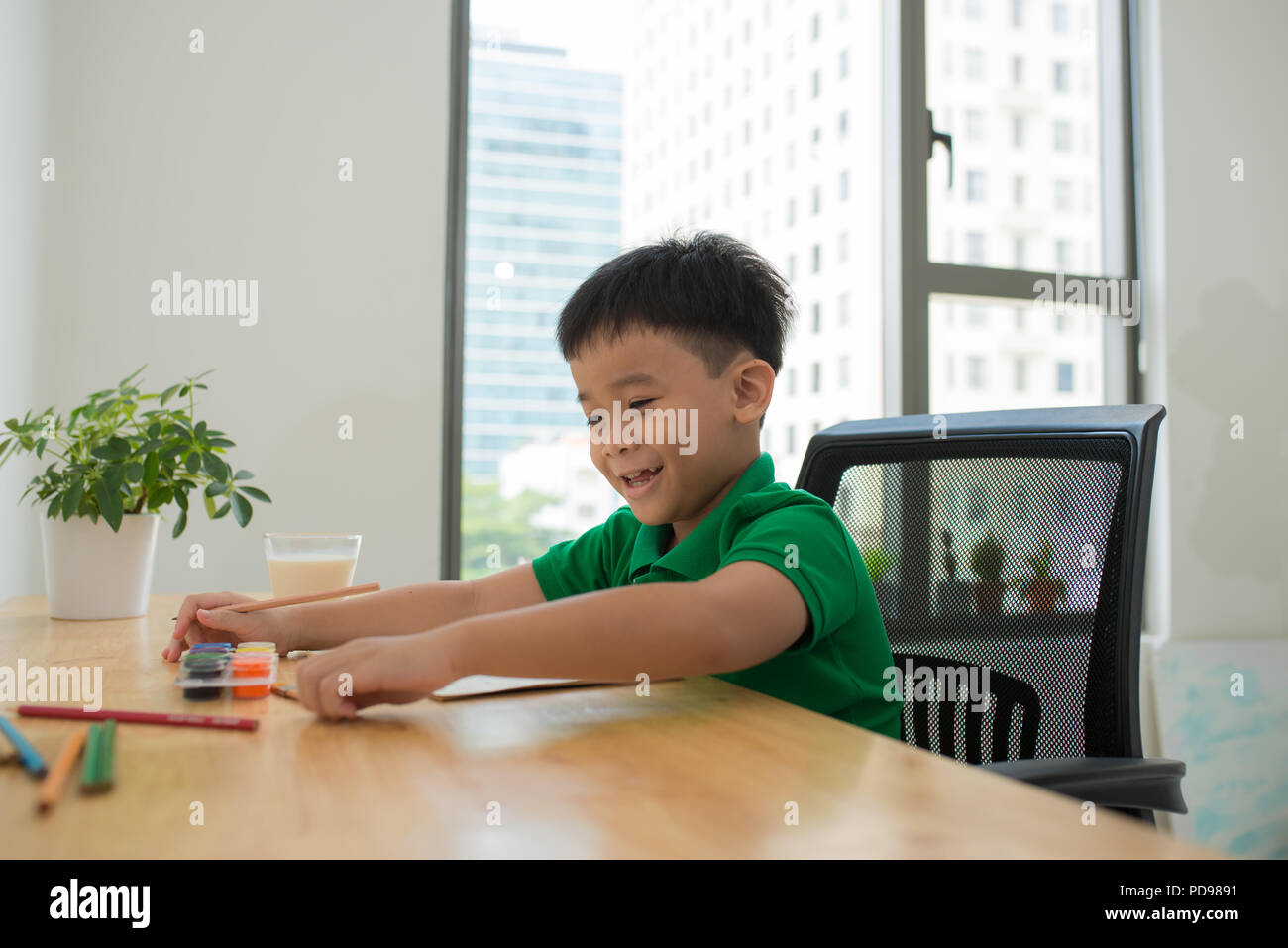 Cute smiling boy doing homework, coloring pages, writing and painting . Children paint. Kids draw. Preschooler with books in the library. Colorful pen Stock Photo
