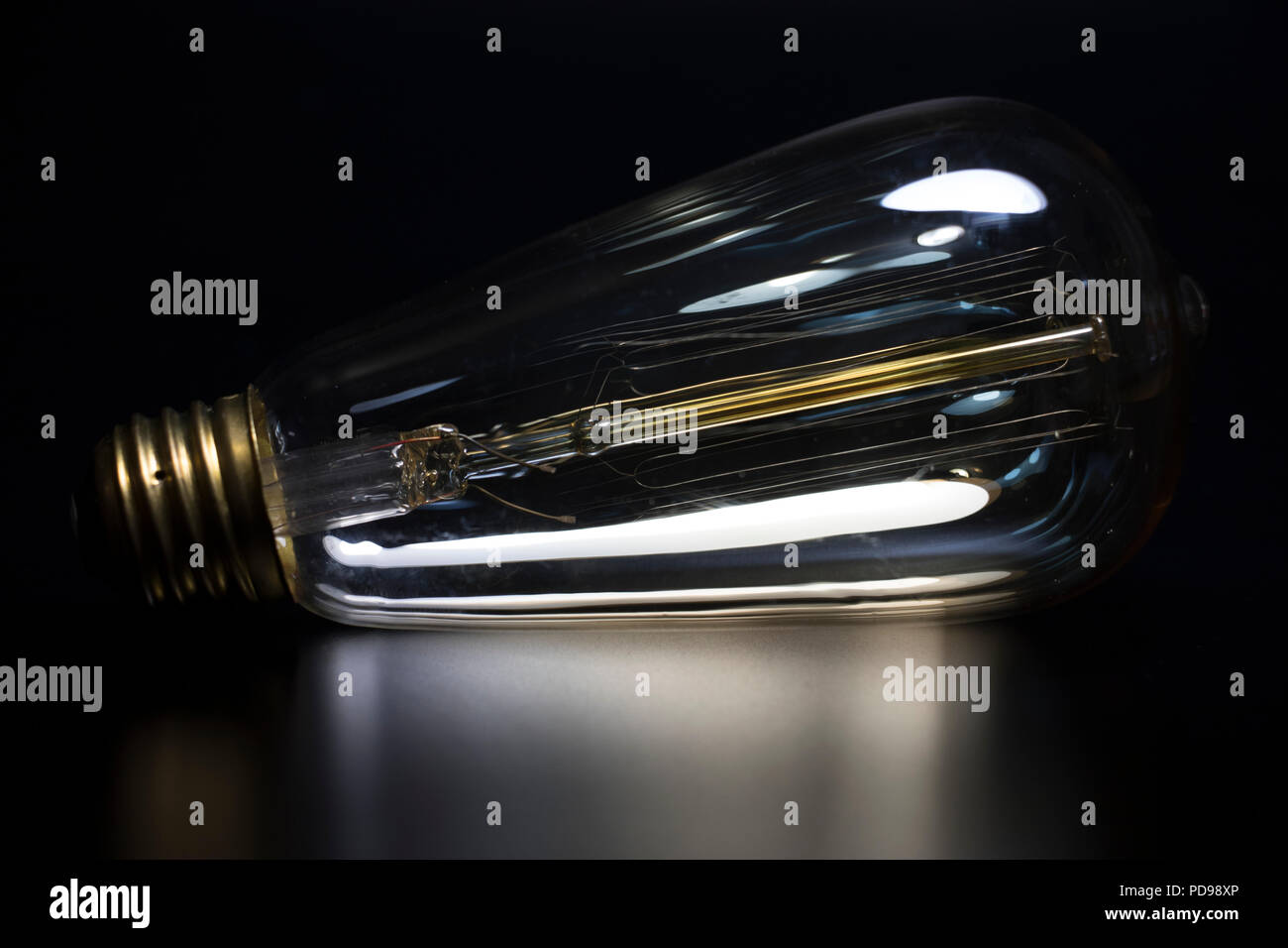 Tungsten light bulb on black reflective surface. Bright idea classic