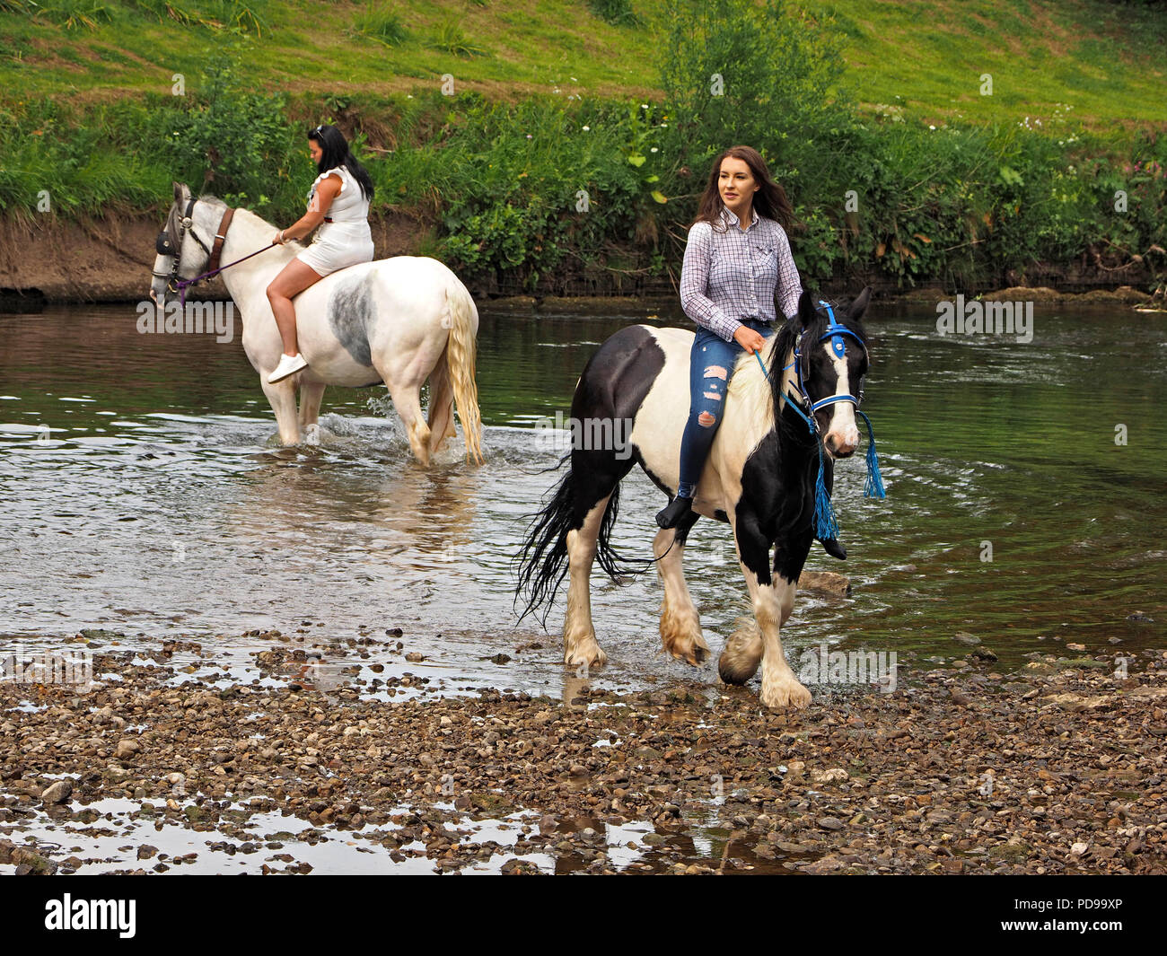 two posing bareback female riders swimming horses in River Eden at the