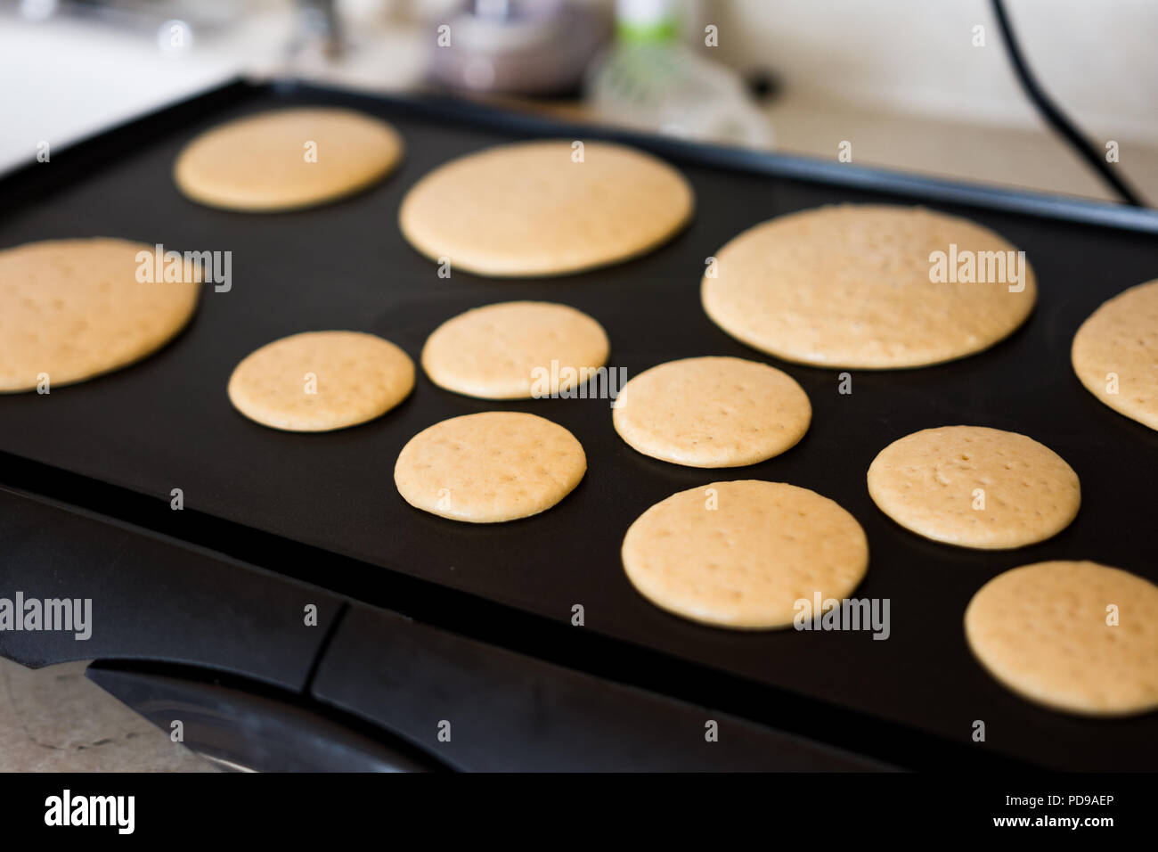 Cooking wheat pancakes for american breakfast on black griddle Stock Photo