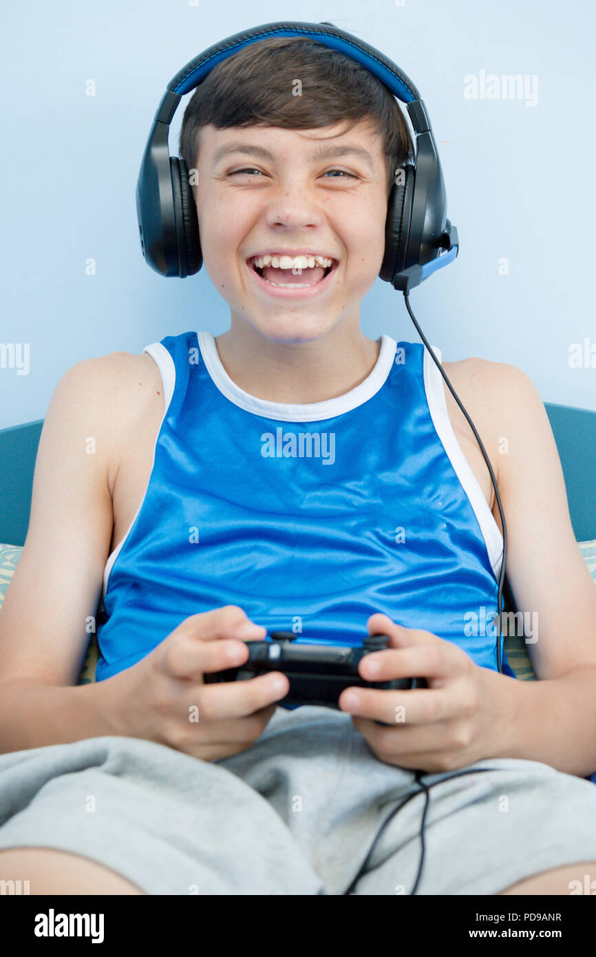 Teenage boy playing a video game while on his bed Stock Photo - Alamy