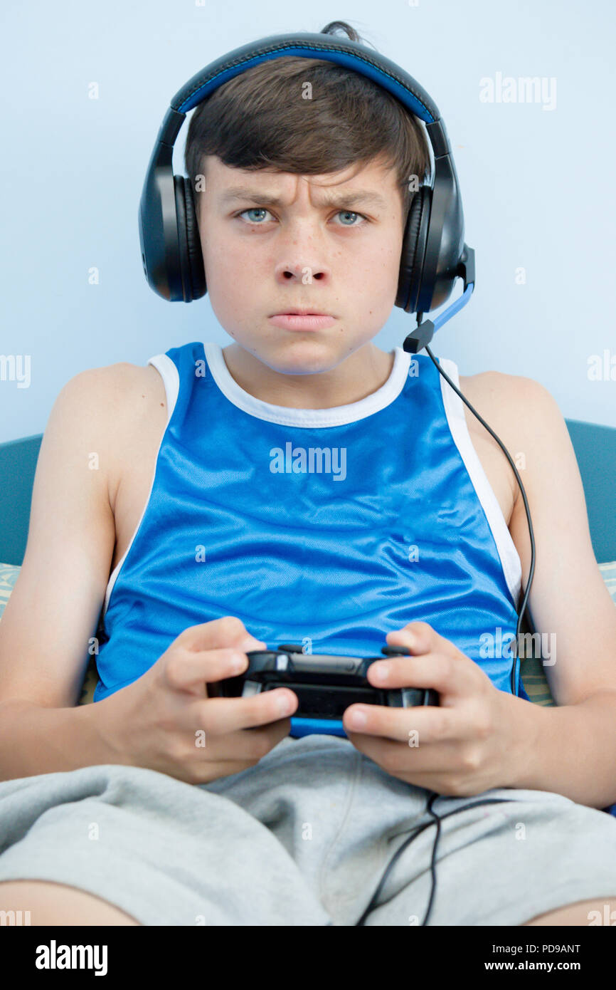 Teenage boy playing a video game while on his bed, losing Stock Photo ...