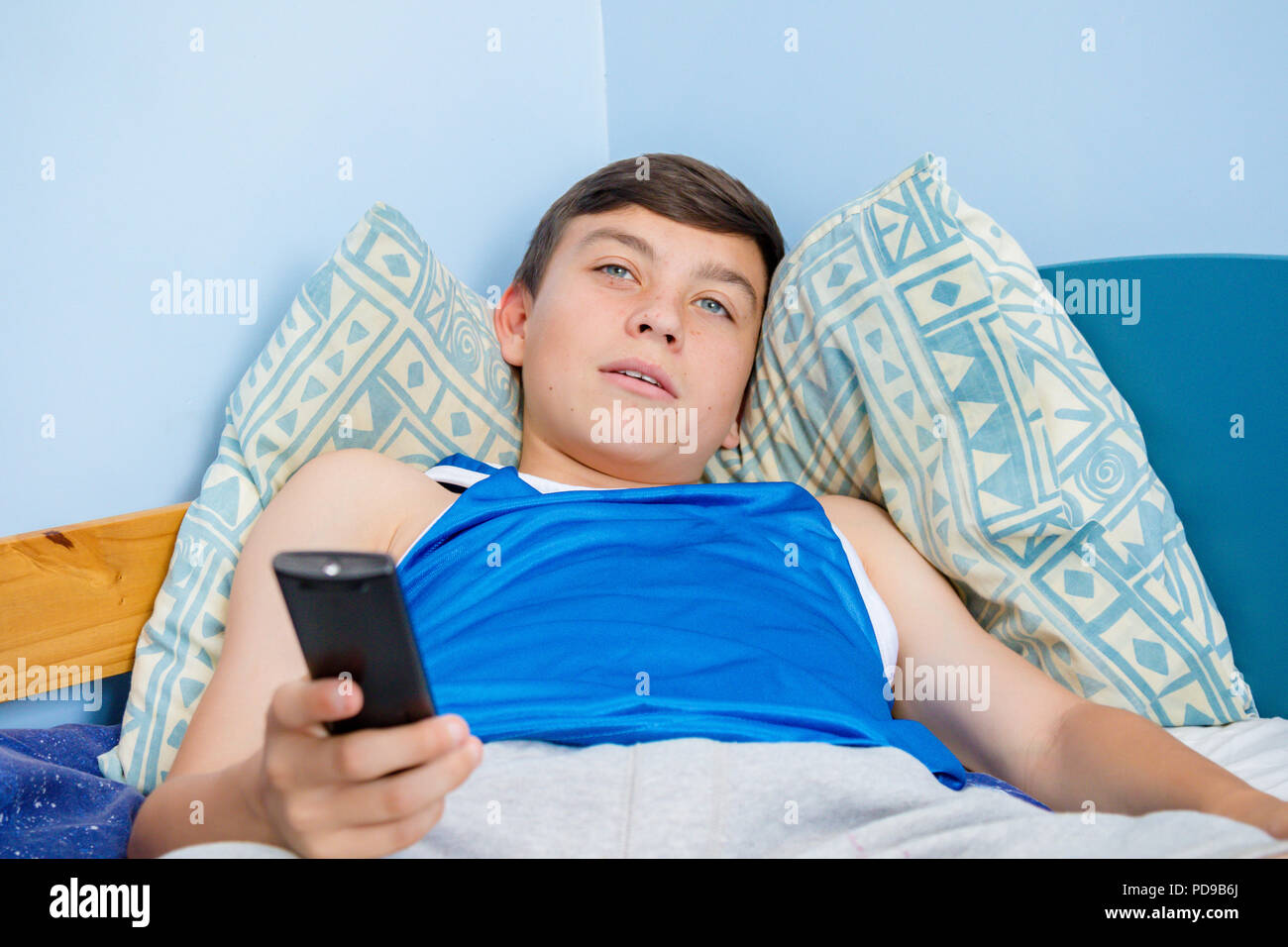 Caucasian teenage boy flicking through tv channels with a remote control Stock Photo