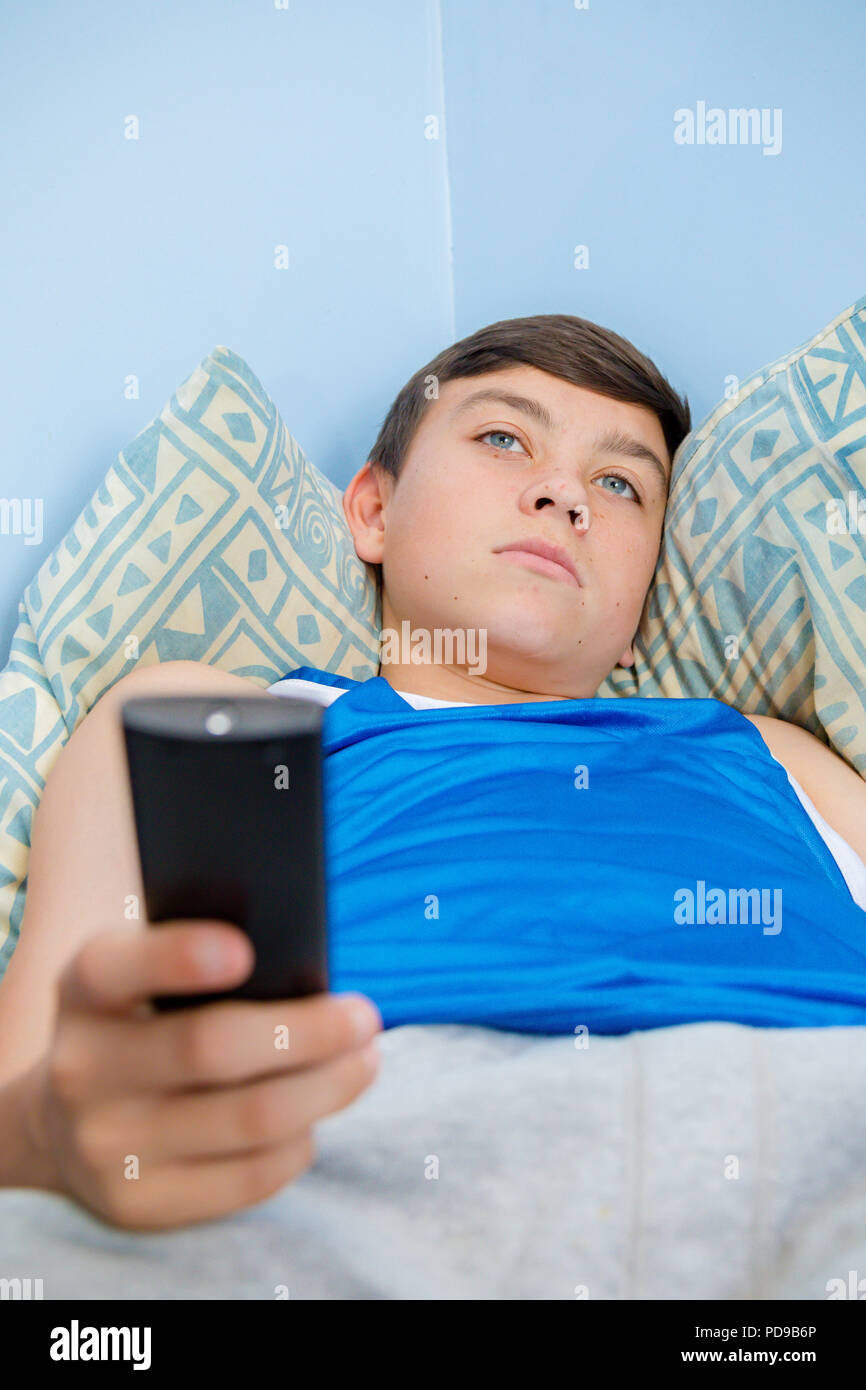Caucasian teenage boy flicking through tv channels with a remote control Stock Photo