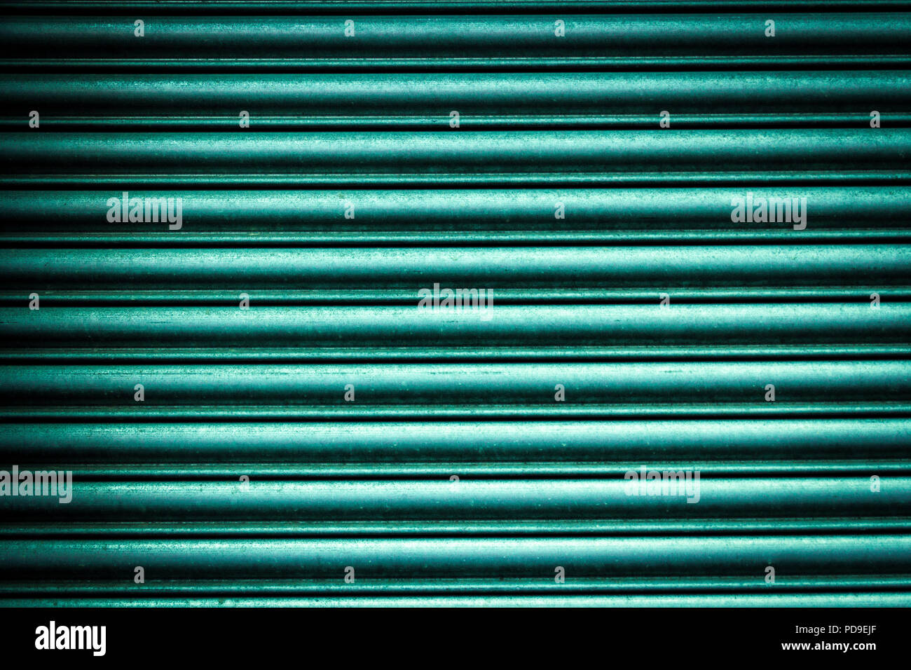 Close-up of the wavy aluminum metal surface background in green, turquoise, teal color in the sunlight Stock Photo