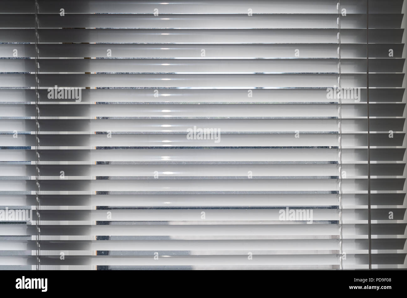 Closed white metal venetian blinds hiding inside world of home from prying views of outside, afraid of going outside. Stock Photo