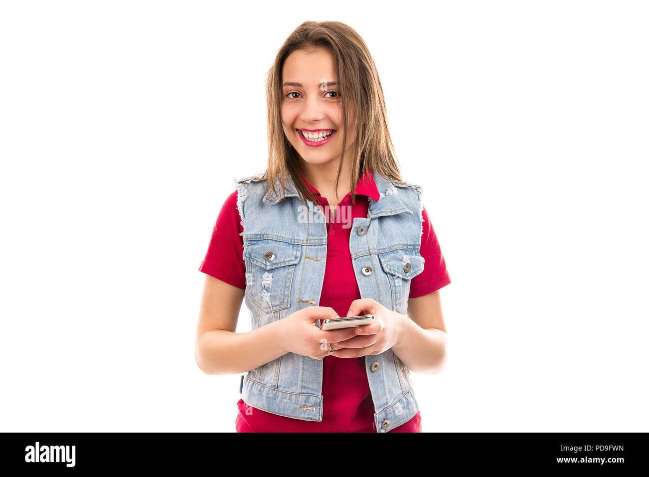 Pretty happy young woman in casual denim holding and using smartphone ...