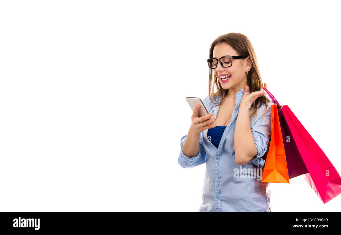 Smiling young woman with colorful paper bags using smartphone and shopping online isolated on white background Stock Photo