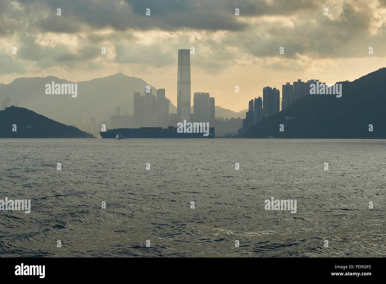 A Container Ship Passes In Front Of The Hong Kong Skyline As It Exits The East Lamma Shipping Channel And Head To Towards The Container Port. Stock Photo