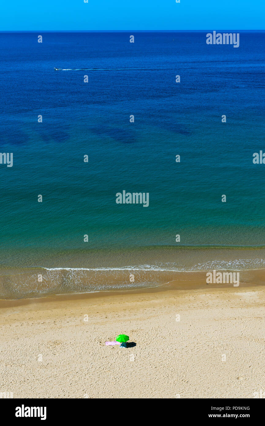 Solitary parasol on an empty sandy beach near Praia da Luz, Algarve,  Portugal Stock Photo - Alamy