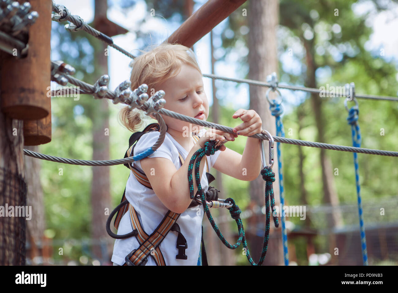 Baby girl runs an obstacle course in a cable park. Stock Photo
