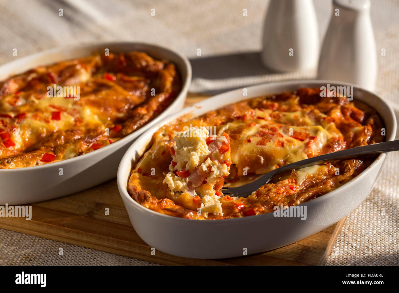 Two trays with baked omelette made from cheese, eggs, ham and red