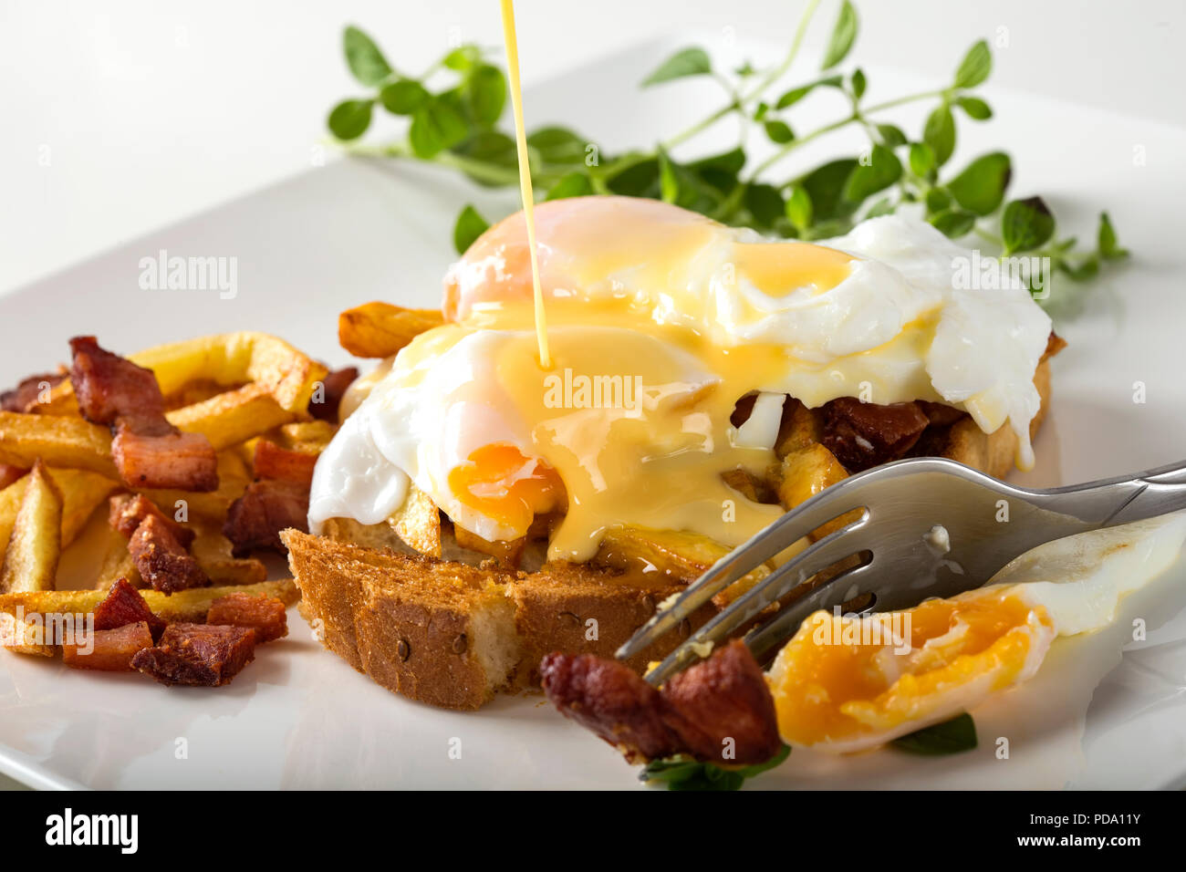 Toast sandwich with two poached eggs, French fries and bacon on the